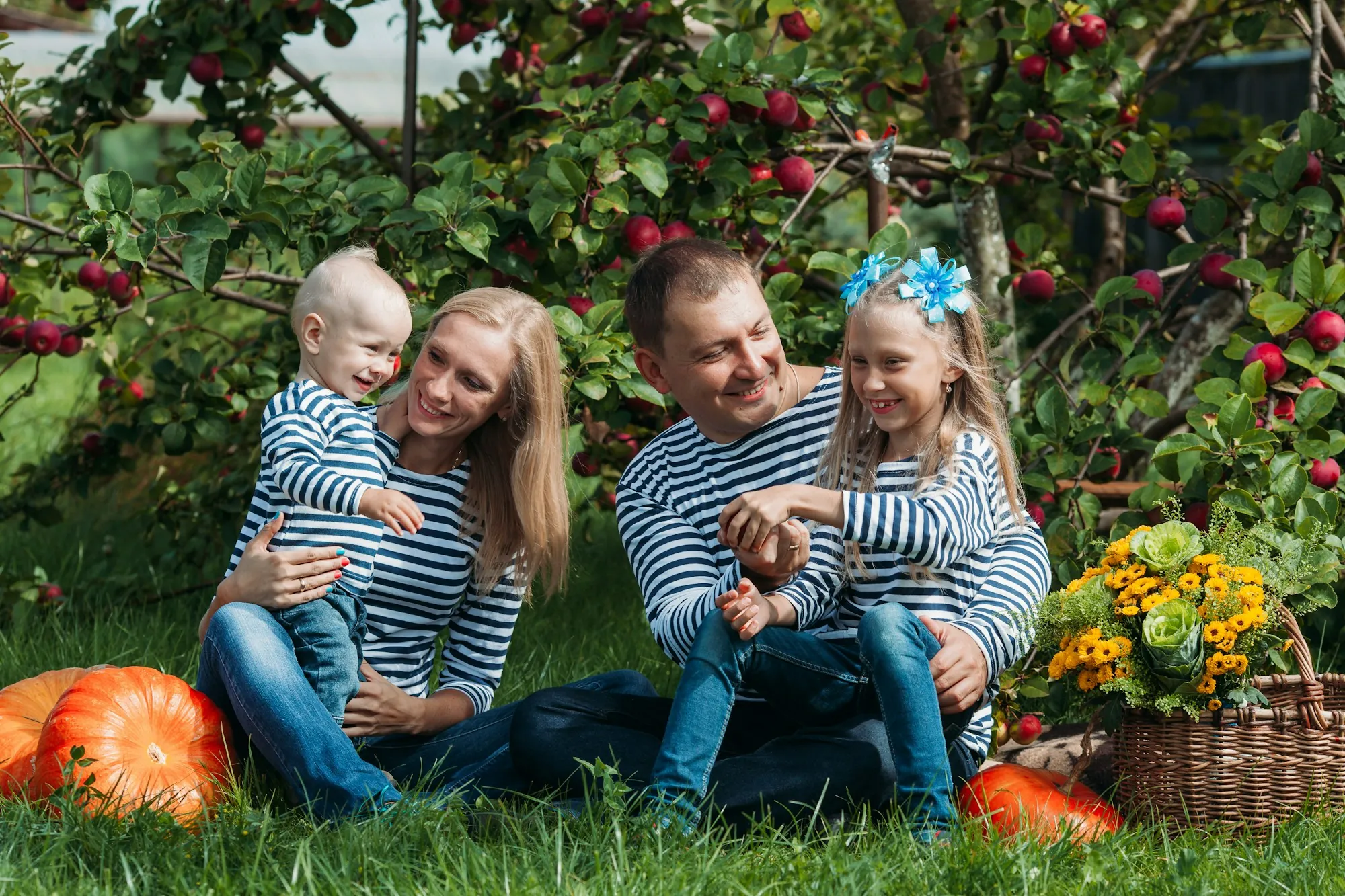 Family in striped shirts sitting in a garden with pumpkins